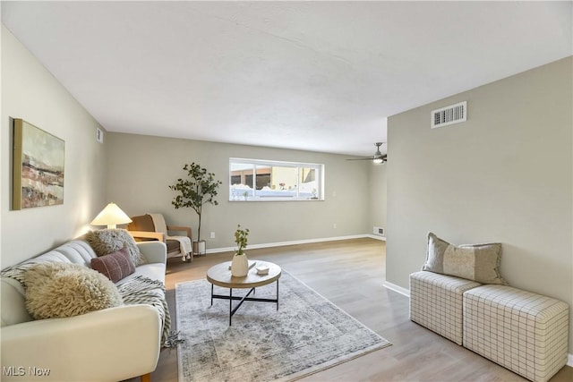 living area with light wood-style floors, baseboards, visible vents, and ceiling fan