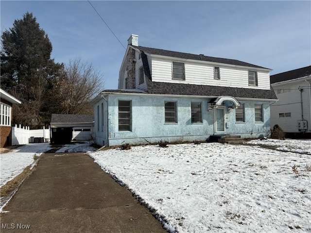 colonial inspired home featuring roof with shingles, a chimney, a gambrel roof, fence, and a garage