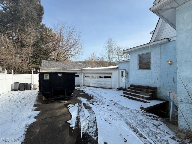 snow covered garage with fence