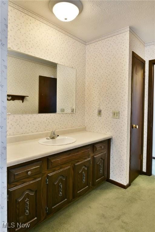 bathroom featuring crown molding, a textured ceiling, vanity, and wallpapered walls