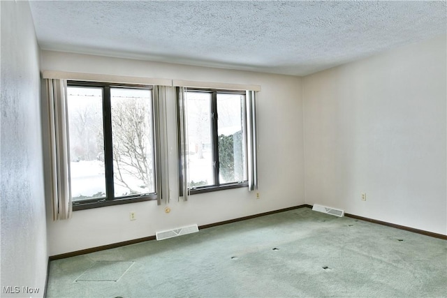 carpeted empty room with a healthy amount of sunlight, baseboards, and visible vents