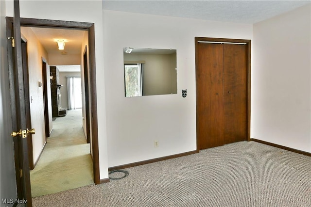 unfurnished room with baseboards and light colored carpet