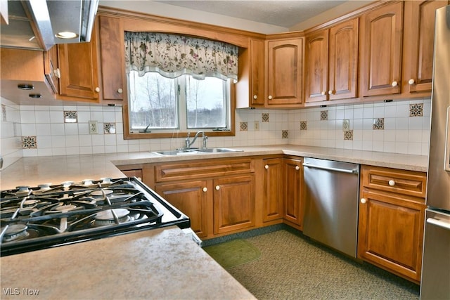 kitchen featuring light countertops, appliances with stainless steel finishes, a sink, and brown cabinets