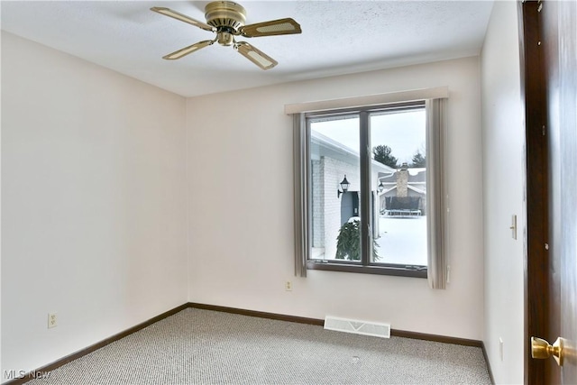 carpeted spare room with baseboards, visible vents, ceiling fan, and a textured ceiling