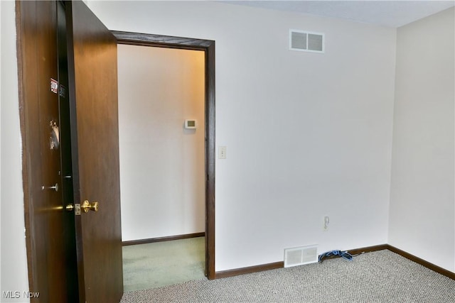 carpeted spare room featuring visible vents and baseboards