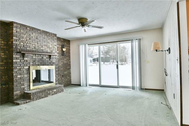 unfurnished living room featuring light colored carpet, a brick fireplace, ceiling fan, a textured ceiling, and baseboards