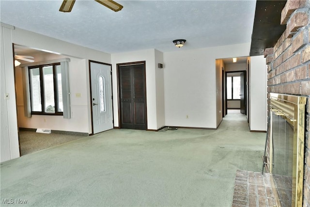 unfurnished living room with light carpet, a ceiling fan, baseboards, and a textured ceiling