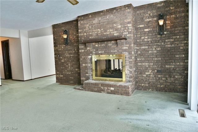 unfurnished living room featuring light carpet, a textured ceiling, a fireplace, and visible vents