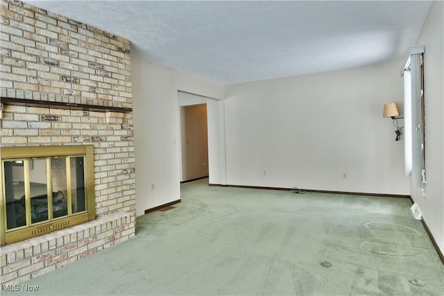 unfurnished living room with carpet, a textured ceiling, a fireplace, and baseboards