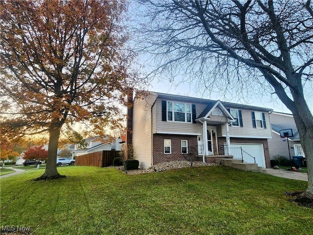 split foyer home with driveway, an attached garage, fence, a yard, and brick siding