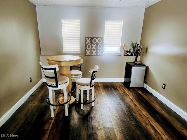 dining space featuring dark wood-style flooring and baseboards