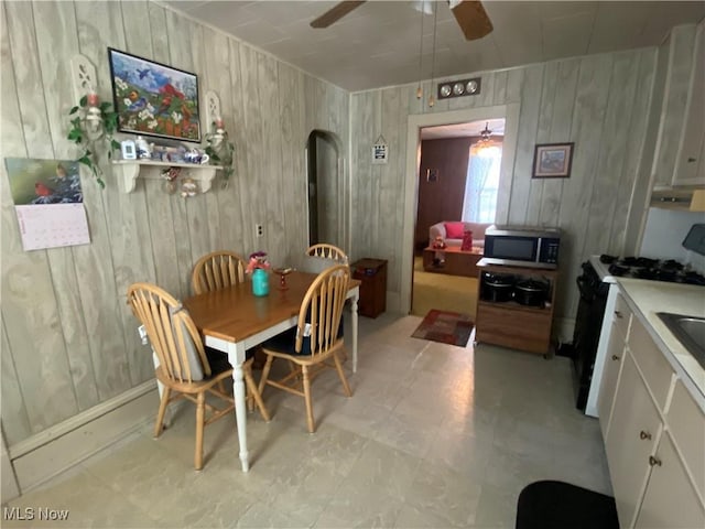 dining space featuring ceiling fan and wood walls