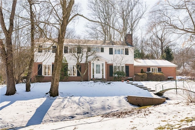 colonial home with a chimney and brick siding