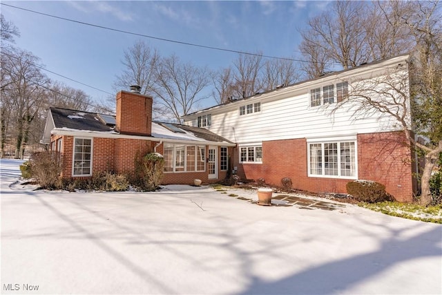 back of house with a chimney and brick siding