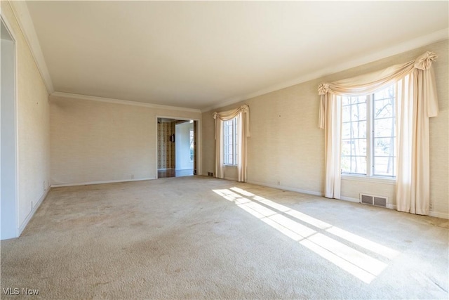 carpeted spare room with ornamental molding, plenty of natural light, visible vents, and baseboards