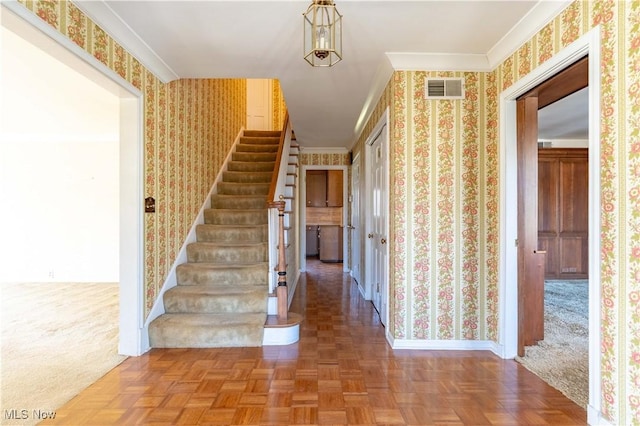 interior space featuring wallpapered walls, baseboards, visible vents, ornamental molding, and stairs