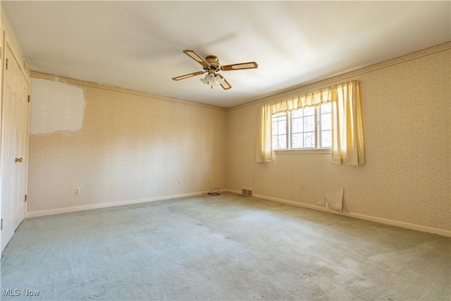 carpeted spare room featuring a ceiling fan, visible vents, baseboards, and wallpapered walls