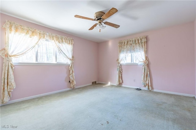 empty room featuring carpet, visible vents, baseboards, and a ceiling fan