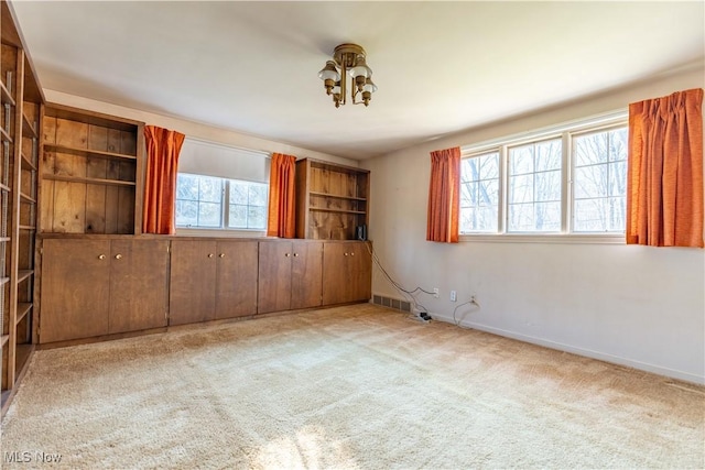 spare room featuring carpet, visible vents, and baseboards