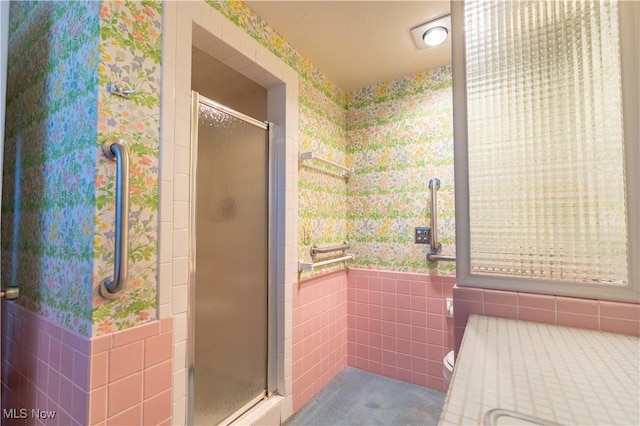 bathroom featuring wallpapered walls, a shower stall, and tile walls