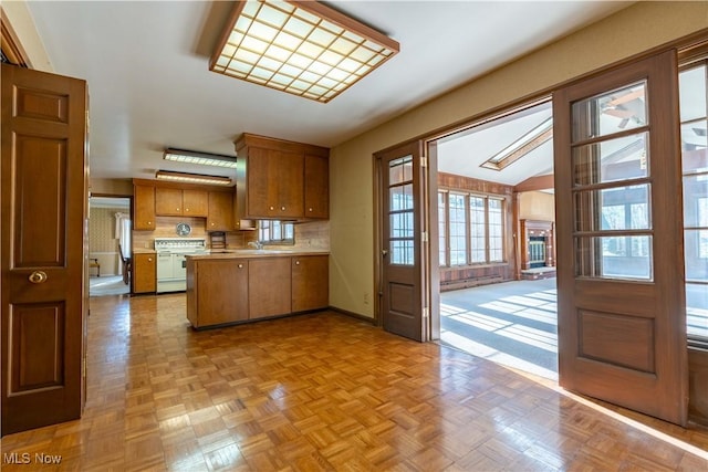 kitchen with brown cabinets, a peninsula, light countertops, white electric range, and backsplash