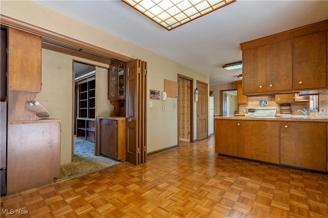 kitchen with light countertops, brown cabinetry, a peninsula, and freestanding refrigerator