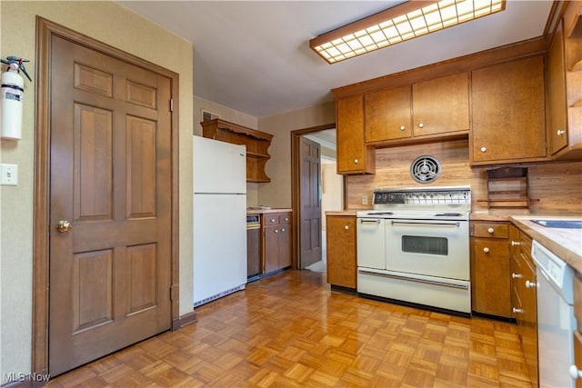 kitchen with white appliances, tasteful backsplash, brown cabinetry, light countertops, and open shelves