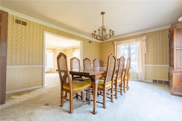 carpeted dining area with wallpapered walls, visible vents, and wainscoting