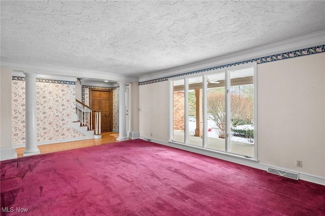 carpeted spare room featuring crown molding, a textured ceiling, visible vents, and ornate columns