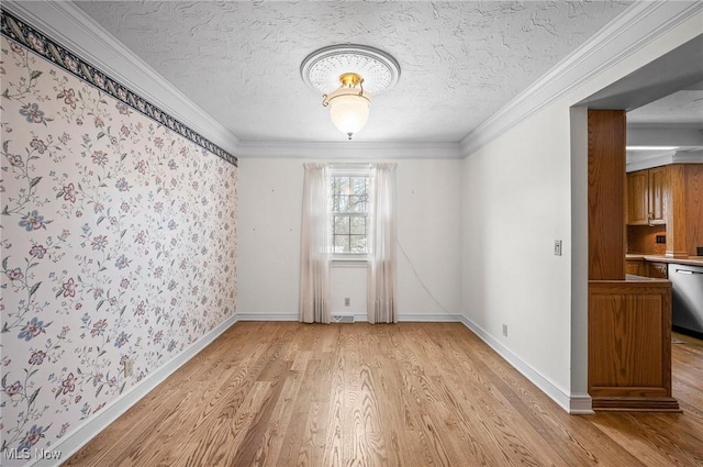 empty room featuring ornamental molding, baseboards, light wood-style flooring, and a textured ceiling