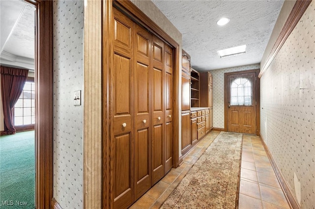 interior space featuring a textured ceiling, baseboards, light tile patterned flooring, and wallpapered walls