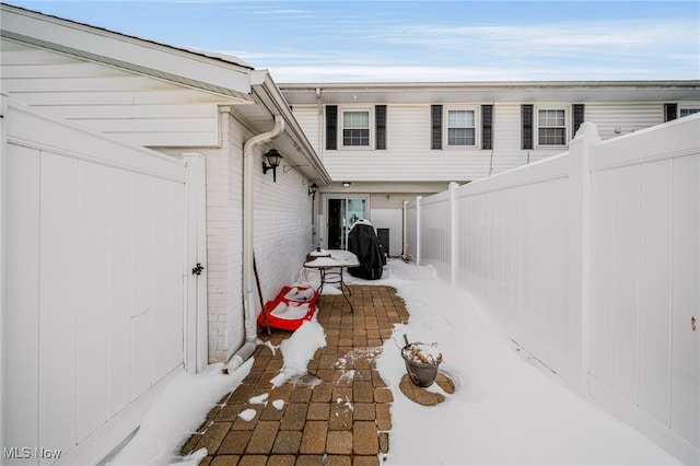 snow covered patio featuring a fenced backyard