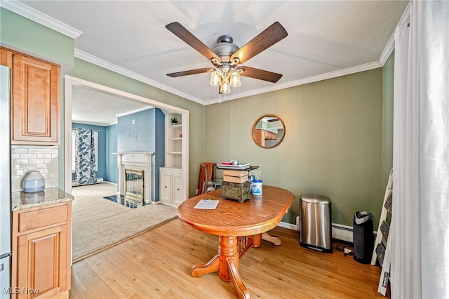 dining room featuring light wood finished floors, baseboards, a fireplace with flush hearth, ornamental molding, and baseboard heating