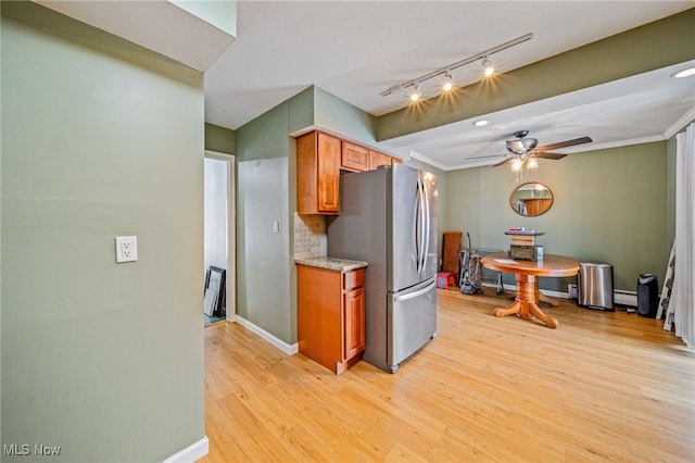 kitchen featuring tasteful backsplash, brown cabinets, freestanding refrigerator, light countertops, and light wood-type flooring