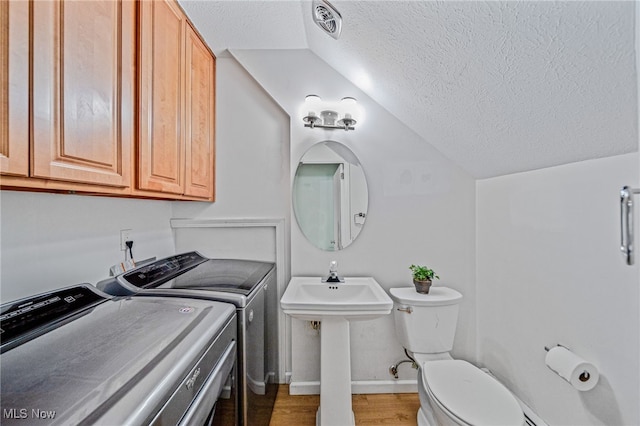 bathroom with washing machine and clothes dryer, lofted ceiling, visible vents, toilet, and a textured ceiling