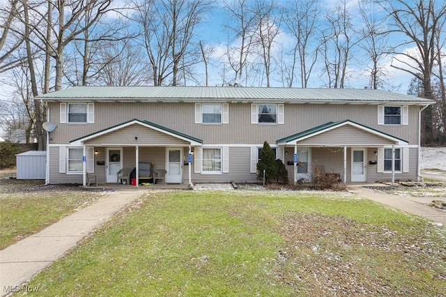 view of front of home with covered porch, metal roof, and a front yard