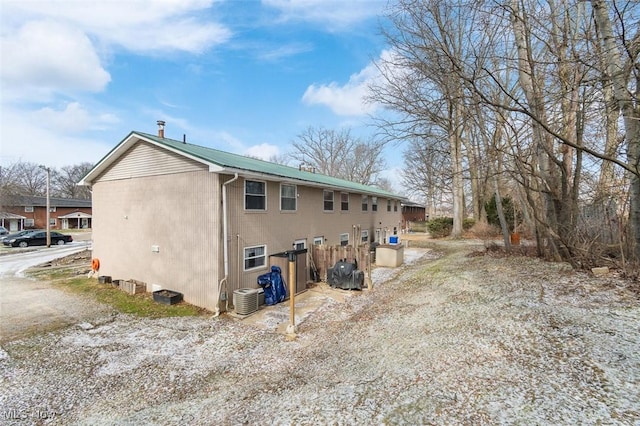 view of side of property featuring metal roof and central AC unit