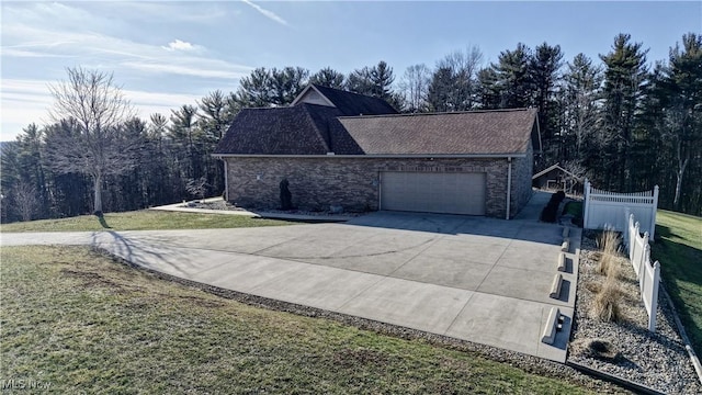 view of side of home with a garage, fence, concrete driveway, and a yard