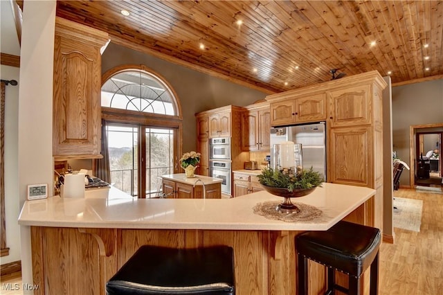 kitchen with wood ceiling, light countertops, appliances with stainless steel finishes, a center island, and crown molding