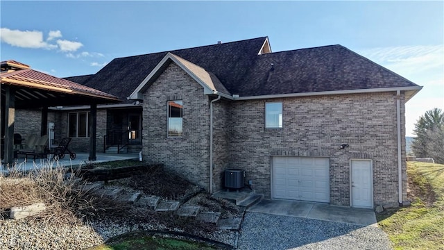 exterior space featuring a patio area, a shingled roof, central AC, and brick siding