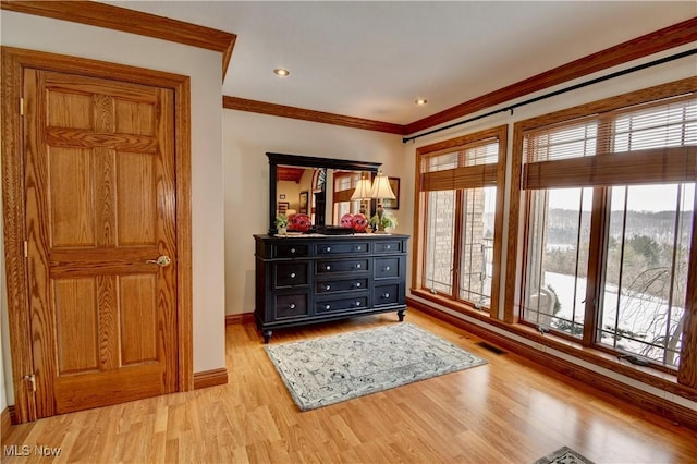 interior space with light wood-style floors, baseboards, visible vents, and crown molding