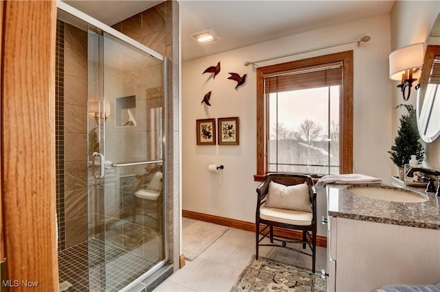 bathroom with a stall shower, vanity, baseboards, and tile patterned floors