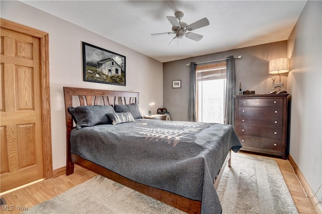 bedroom with light wood finished floors, baseboards, and a ceiling fan