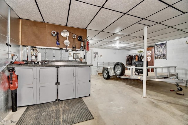 interior space with a drop ceiling and concrete block wall