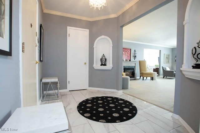 foyer entrance with a chandelier, baseboards, marble finish floor, a glass covered fireplace, and crown molding