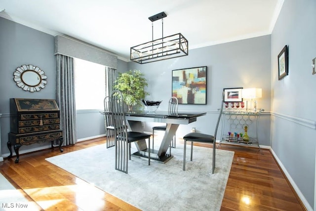 dining area with an inviting chandelier, baseboards, crown molding, and wood finished floors