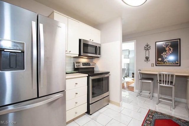 kitchen featuring light countertops, appliances with stainless steel finishes, backsplash, and white cabinets