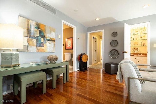 office space featuring a sink, baseboards, visible vents, and wood finished floors