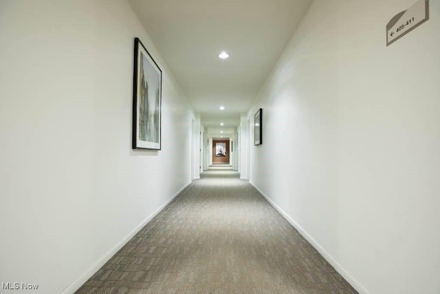 corridor featuring recessed lighting, dark carpet, and baseboards