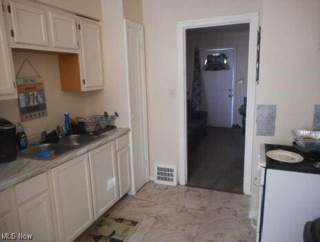 kitchen with white cabinets, visible vents, light countertops, and a sink